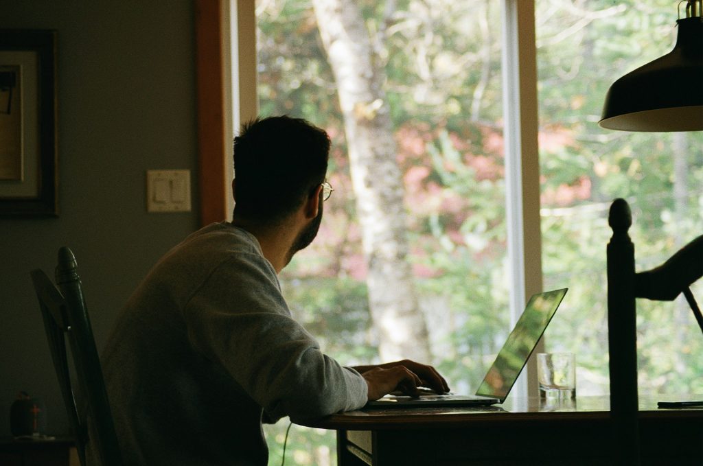 Hombre sentado en una mesa con una computadora manejando negocios rentables desde casa.